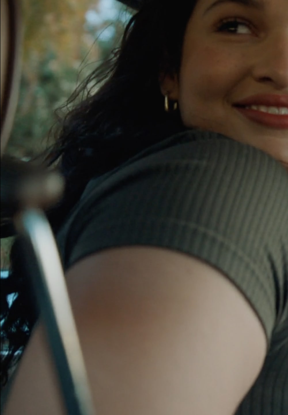 Woman with curly hair smiling in the back seat of a car